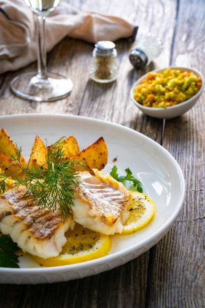 istock Fried codfish loin fried potatoes and cabbage salad served on white plate on wooden table. 2194102984