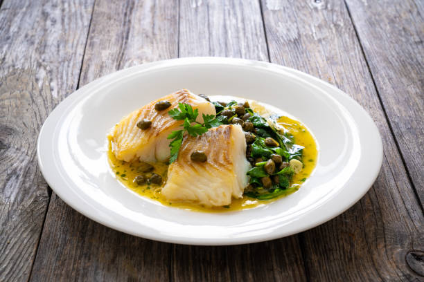 istock Fish dish - fried cod with spinach and capers in saffron sauce on wooden table 2194103637