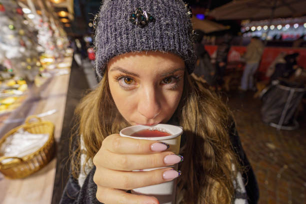 Young girl drinking wine and looking into the camera, advent fair, Hungary, Budapest, wide angle lens