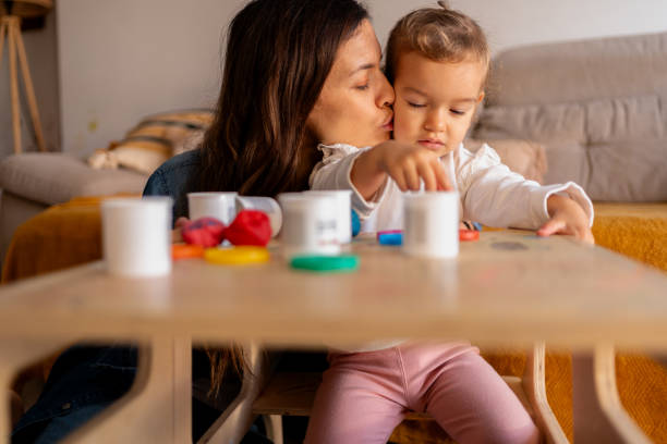 istock Mother kissing her daughter while playing with modeling clay at home 2194109707