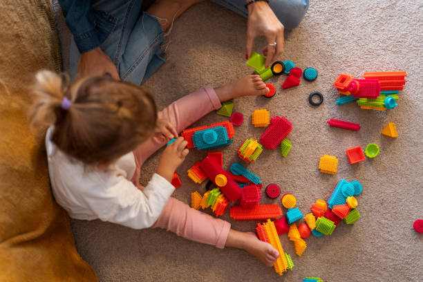 istock Mother and daughter playing with colorful bristle blocks on carpet 2194109736
