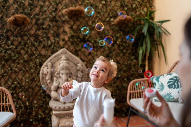 istock Little girl looking up while playing with soap bubbles in a garden 2194109756