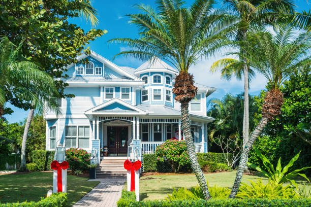 New tile-roofed home with palm trees and lush tropical foliage. Florida.