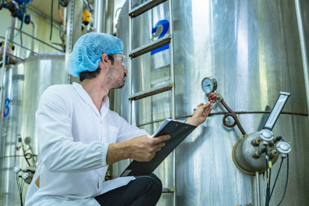 istock Worker examining an industrial tank and recording data on a clipboard, emphasizing the importance of safety, quality assurance, and technological advancement in industrial environments. 2194113847