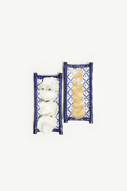 Two intricately designed blue ceramic trays displaying traditional Thai appetizers, Featuring steamed dumplings and crispy crackers, Elegantly arranged on a white background for a minimalist presentation