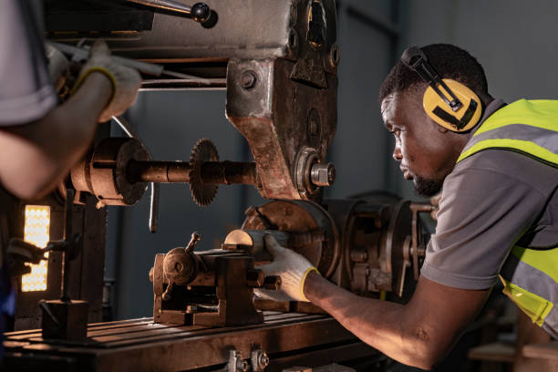istock Focused industrial technician operating heavy machinery with precision. Wearing ear protection and safety gear, the professional works in a brightly lit workshop, emphasizing safety and expertise. 2194119402