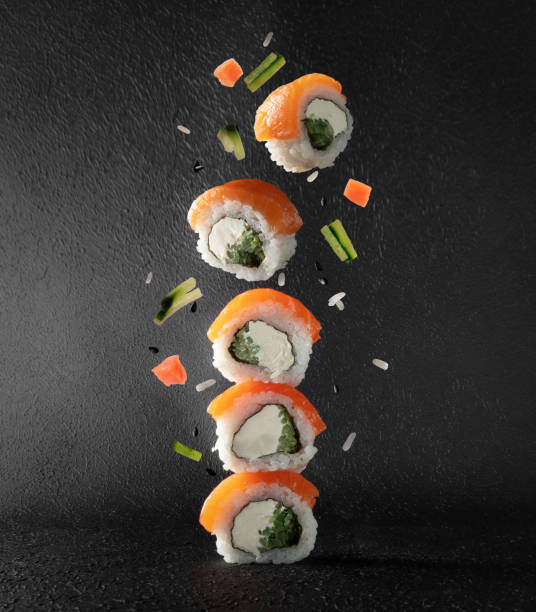 istock Sushi rolls with salmon falling down on a dark background. Sushi rolls levitate in the air 2194126368