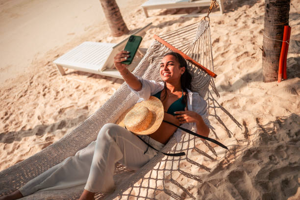 istock Relaxed Hispanic Woman on Beach Hammock Taking Selfie 2194129528
