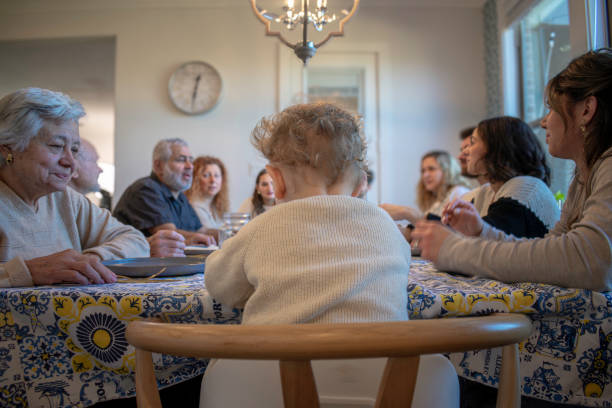 istock Little boy sits at table with multigenerational family 2194131267