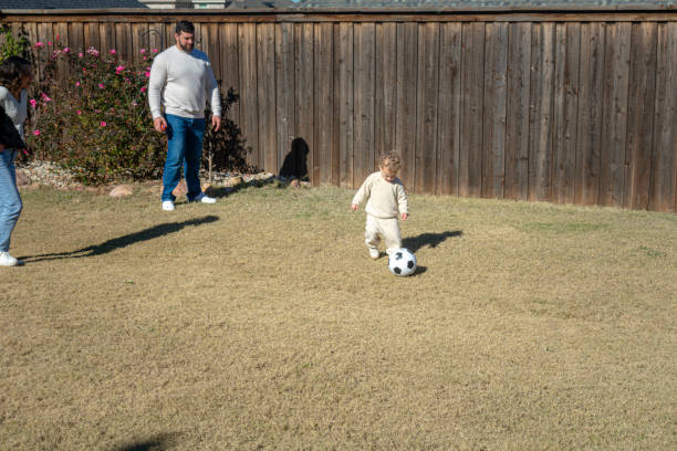 istock Little boy kicks ball in back yard 2194131341