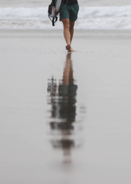 Youn man is walking on Canggu beach after surfing ocean.Canggu beach - Bali Island.