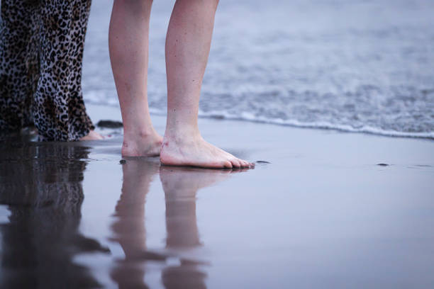 A women are standing on sand near by ocean.Canggu beach - Bali Island - Indonesia.