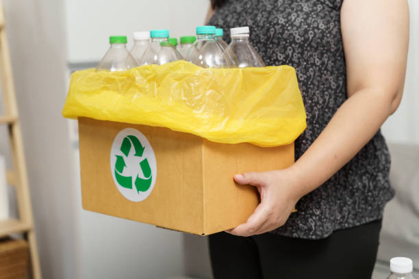 istock Home recycle eco green zero concept Woman throwing empty plastic bottle in recycling bin with yellow garbage bags at home. 2194140064