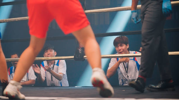 Top view of a weary boxer heeds their trainer's words of encouragement during a grueling boxing match.