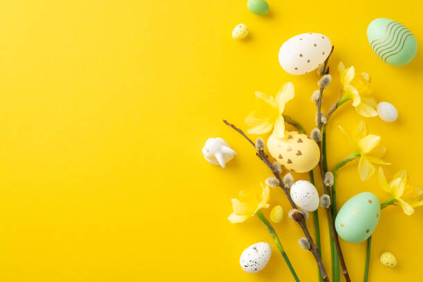 istock Colorful painted Easter eggs and fresh spring flowers creatively arranged on a yellow backdrop 2194161524