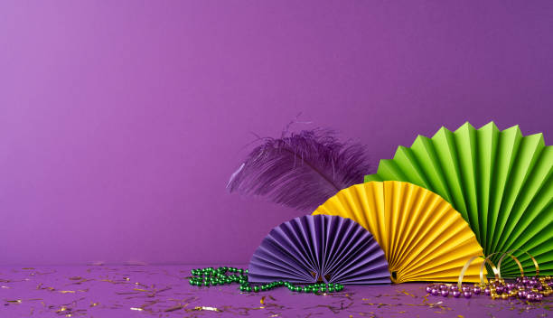 istock Bright and festive Mardi Gras side view decorations with beads, feathers, and paper fans on a purple background 2194161579
