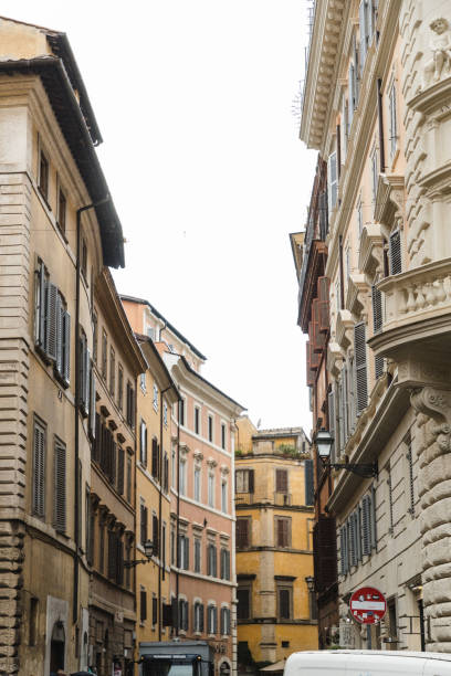 A charming Roman street flanked by colorful historic buildings with intricate balconies and shutters. The scene captures the quintessential essence of Italian architecture, with its warm tones and timeless details, inviting you to wander and explore.