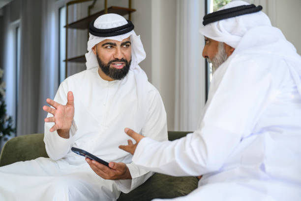 istock Emirati man holding smart phone, gesturing and explaining to his father 2194169703