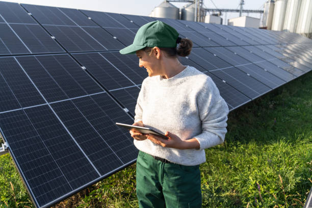 istock Female farmer with digital tablet on a modern farm using solar panels. Agricultural silos in the background 2194170996