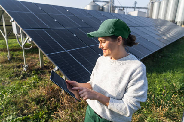 istock Female farmer with digital tablet on a modern farm using solar panels. Agricultural silos in the background 2194171397