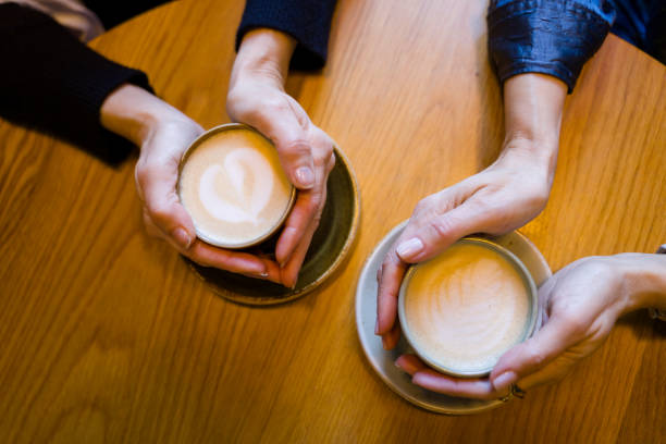 istock Two women holding latte art coffee cups at cafe table 2194173864