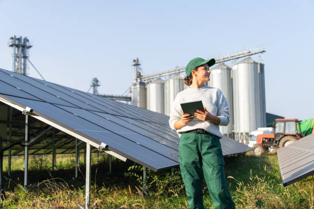istock Female farmer with digital tablet on a modern farm using solar panels. Agricultural silos in the background 2194175268