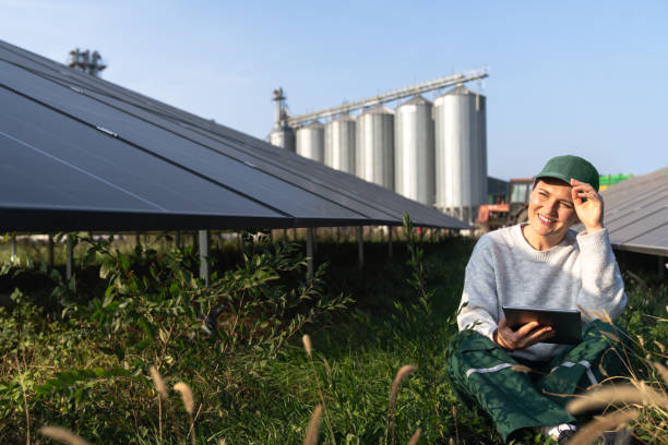 istock Female farmer with digital tablet on a modern farm using solar panels. Agricultural silos in the background 2194175269