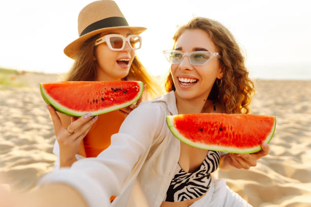 istock Smiling two women eating watermelon on beach. 2194176805