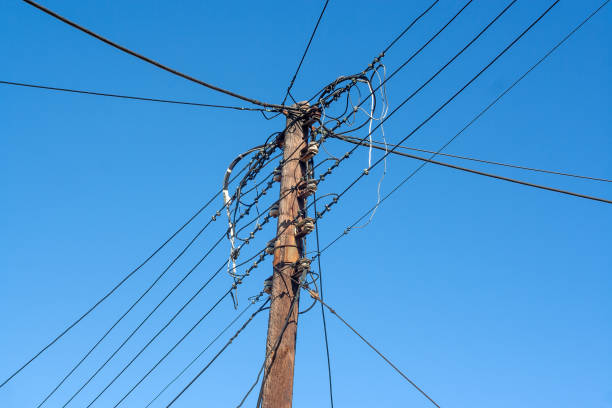 Low angle view of wooden power poles on a clear, sunny day