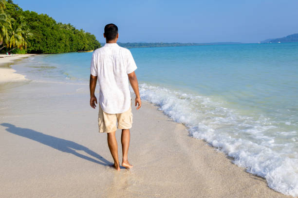 istock isolated man walking at pristine white sand beach with rolling sea waves at morning from flat angle 2194180527