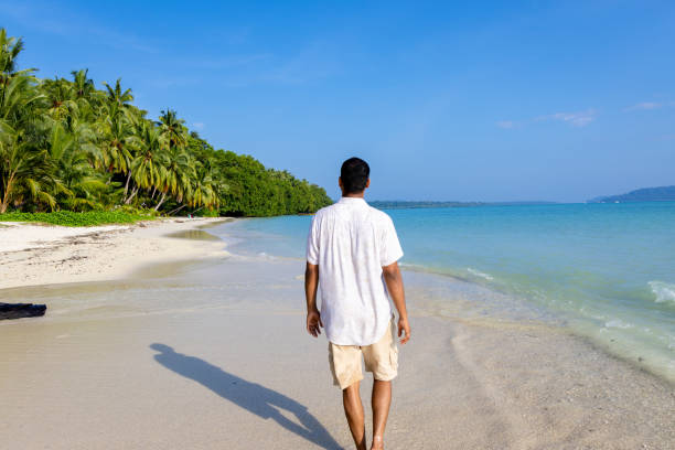 istock isolated man walking at pristine white sand beach with rolling sea waves at morning from flat angle 2194180529