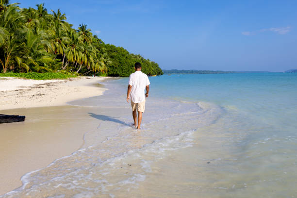 istock isolated man walking at pristine white sand beach with rolling sea waves at morning from flat angle 2194180535