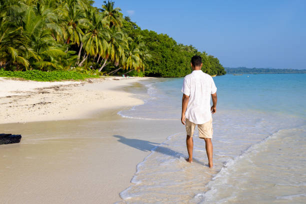 istock isolated man walking at pristine white sand beach with rolling sea waves at morning from flat angle 2194180537