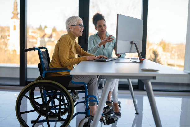 istock Disabled woman in wheelchair looking at computer, discussing startup project with interracial team 2194180931