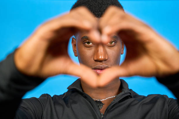 istock Young man making heart shape with hands on blue background 2194183044