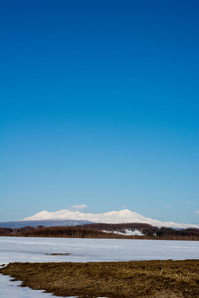 Snow-covered fields and snowy mountains on a sunny spring day