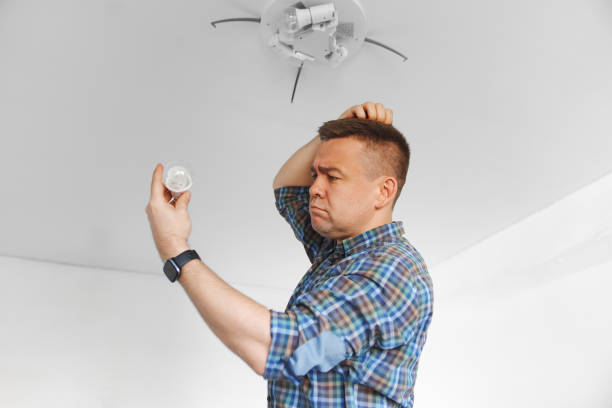istock A puzzled man in a plaid shirt replacement of light bulbs in a ceiling lamp 2194184010