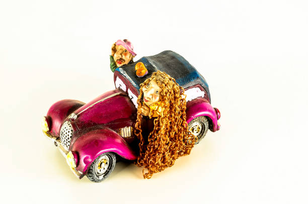 A pink car with a woman and a dog inside. The woman has long hair. The car is a toy