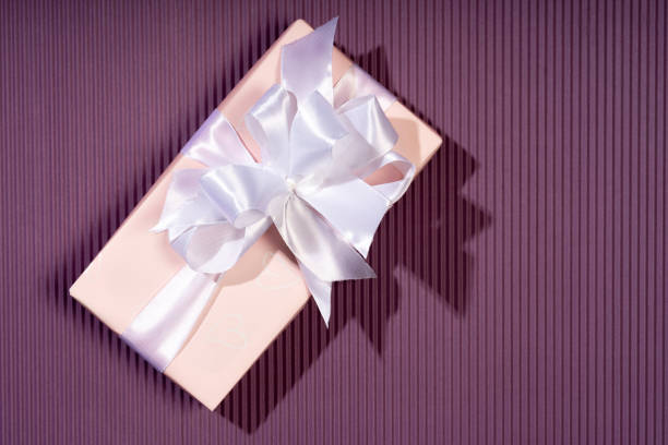 Female hands holding a gift box on a bright background. Gift for Christmas, Valentine's Day, birthday. Beautiful festive background.