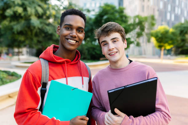 Two young university male students smiling together at camera on campus stock photo