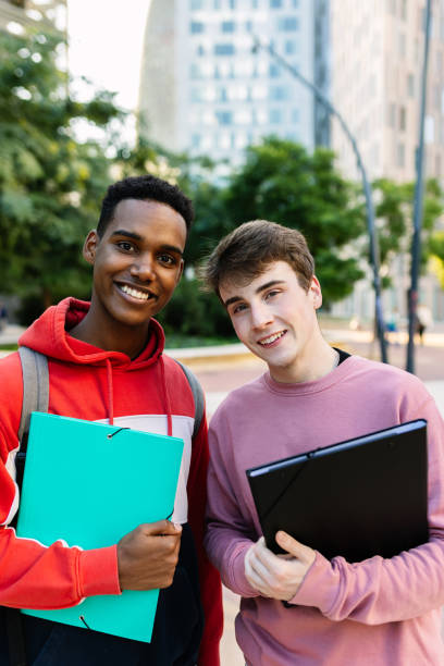 istock Two young university male students smiling together at camera on campus 2194188185