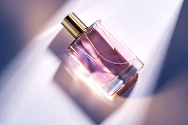 istock A glass perfume bottle with a golden cap on a white background with deep shadows and light effects. Trending showcase , product presentation. 2194188580