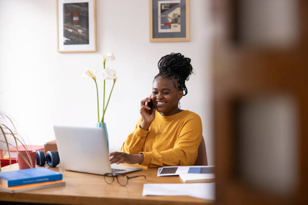 istock Young woman working from home talking on the phone and using laptop 2194188894