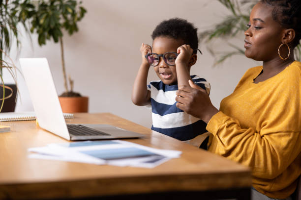 istock Mother helping son with eyeglasses while using laptop at home 2194188920