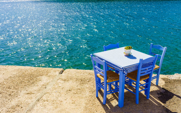 Seaside blue table and chairs open cafe outdoor restaurant in Greece on sea shore. Summer vacation on resort.