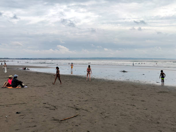 People enjoying walking and playing on Seminyak beach, a famous tourist area on the west coast of Bali, Indonesia