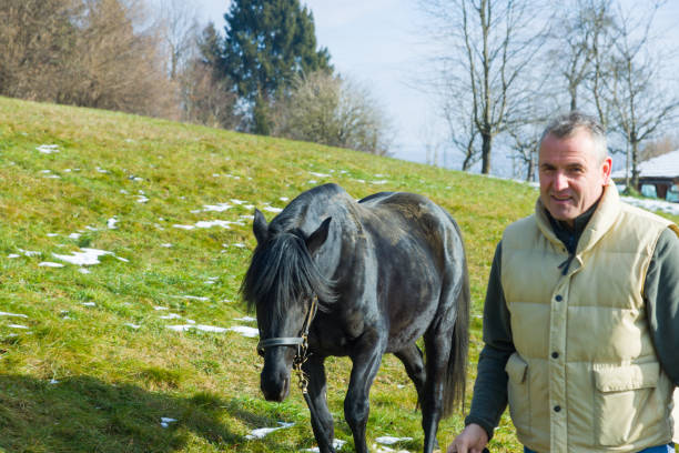 satisfied farm worker hugging his white horse
