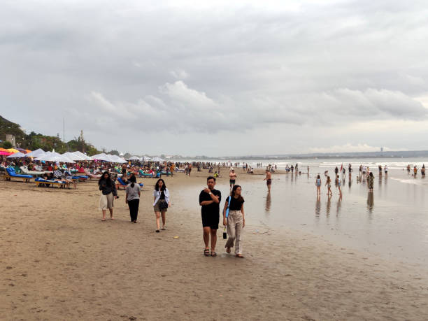 People enjoying walking on Seminyak beach, a famous tourist area on the west coast of Bali, Indonesia