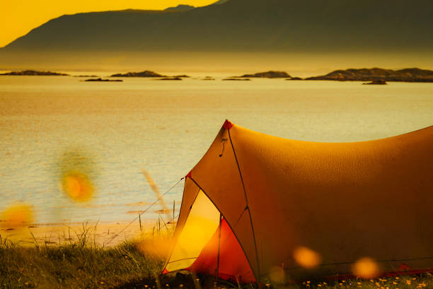 Tent on beach seashore in summer. Camping on ocean shore. Lofoten archipelago Norway. Holidays and travel.