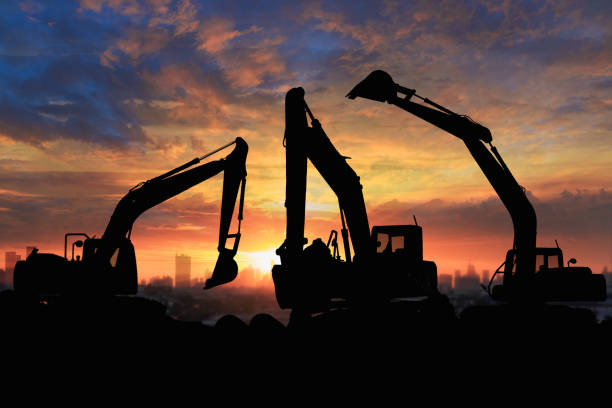 Crawler excavators silhouette are digging the soil in the construction site. on  sunset background